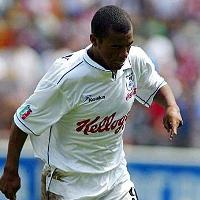 Un  jugador de futbol con uniforme blanco camina rapido en la cancha