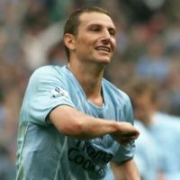 Vemos a un jugador que tiene uniforme azul y sonrie 