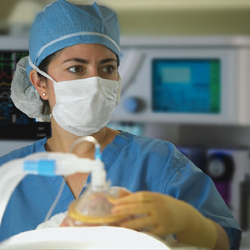 Una enfermera con uniforme azul un tapabocas en una sala de operación