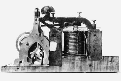 Un pequeño dispositivo con partes metálicas y alambres de cobre sobre una  base