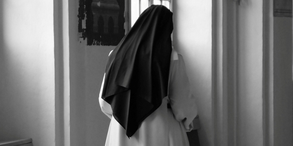 Tenemos a una monja  con su vestido dando la espalda