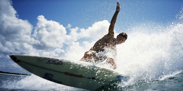 Tenemos aun hombre joven  sobre su tabla de surf