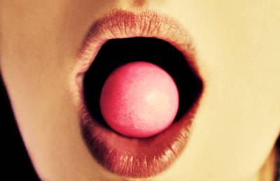 Tenemos a una mujer que hace una bomba con un chicle rosado