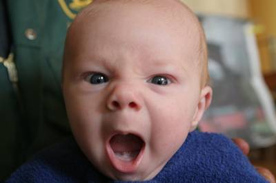 Vemos aun lindo bebe rubio y ojos azules  que da un bostezo muy  grande