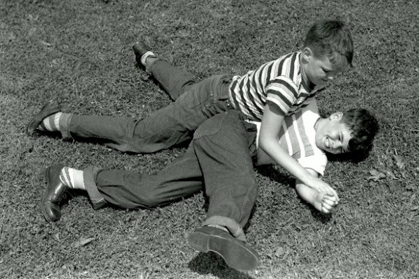 Vemos a dos muchachos muy jovenes que juegan en el piso de hierba