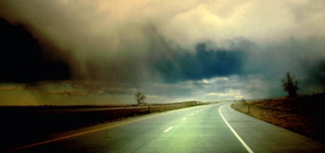 Vemos una carretera con su señalizacion   y al fondo unas nubes de tormenta