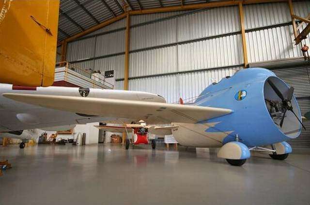 Vemos a un pequeño avión color azul y blanco que esta en un hangar