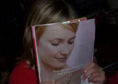 Tenemos una mujer con una revista en la cara donde la modelo de la revista encaja totalmente con la mujer