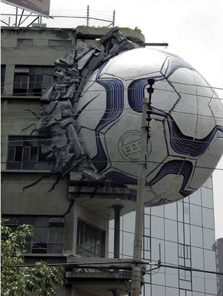 Hay un enorme balón chocado contra un edificio donde se ven partes deterioradas de la pared
