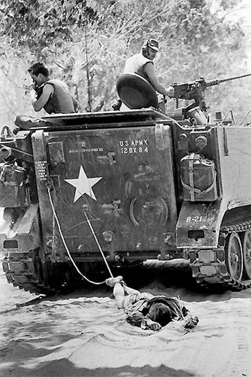 Vemos un tanque de guerra con dos soldados encima  y arrastran un hombre atado con  un lazo al tanque