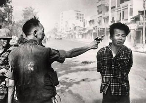 Vemos a dos hombres de etnia oriental donde el mayor le dispara al mas joven en su sien izquierda  