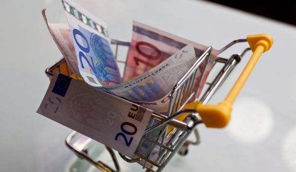 Euros de varias denominaciones en un carrito de compras miniatura