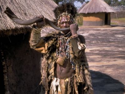 Tenemos aun hombre que toca un largo cuerno vestido con un traje echo como para un ritual