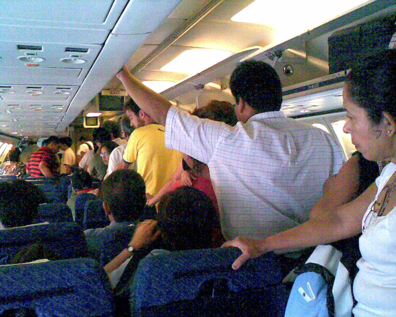 Personas dentro de un avión hacen fila para pasar al baño