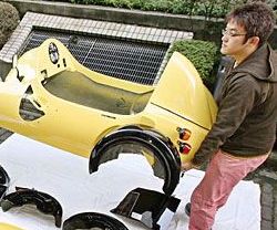 Vemos a una  persona que carga un carro pequeño de color amarillo