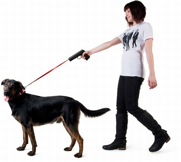 Una mujer muy joven lleva a un perro muy grande negro que lo lleva con una correa que tiene  una pistola