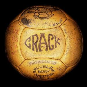 Vemos otro balón antiguo color  amarillo fuerte con la palabra crack al frente y las firmas de sus jugadores 