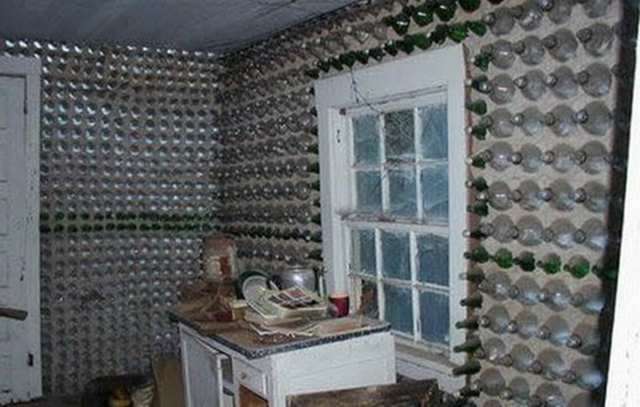 Vemos un cuarto de la una casa hecha con botellas  alli se aprecian muchas  y tambien hayn un escritorio en el cuarto