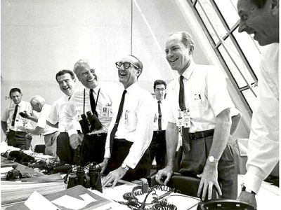 vemos un grupo de hombres en camisa y corbata en una oficina grande   donde todos sonrien con expresión de triunfo
