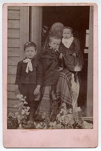 tres hermosos niños vestidos elegantemente uno tiene traje y camisa y lazo y el otro también mira entretenidos algo 