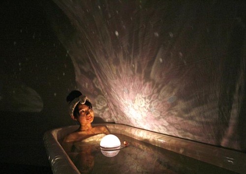 Una mujer en una bañera mira hacia una luz que se ve a través de una cortina