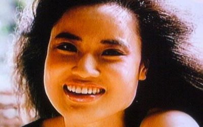 Una mujer con un rostro algo redondeado sonriendo ojos negros pequeños y boca grande labios delgados