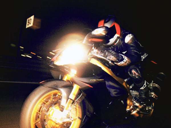 Vemos una moto con su conductor en la noche con sus luces prendiddas