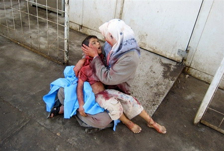 Una mujer con un niño sobre sus piernas llora desconsolada mientras trata de reconfortarlo