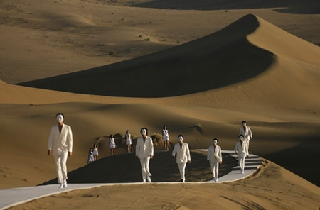 Vemos a unas personas que marchan en fila muy elegantes en el desierto