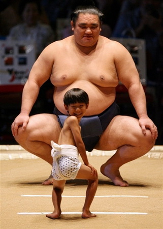 Un hombre corpulento y al pie un pequeño niño a su lado con uniformes iguales 