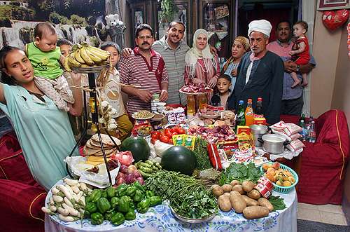Una familia numerosa que come gran variedad pan árabe pimentones  papas verduras frutas sodas atunes 