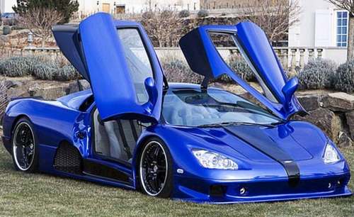 Vemos un carro azul diseño aerodinamico  muestra su estilo de puertas arriba y rines de lujoa