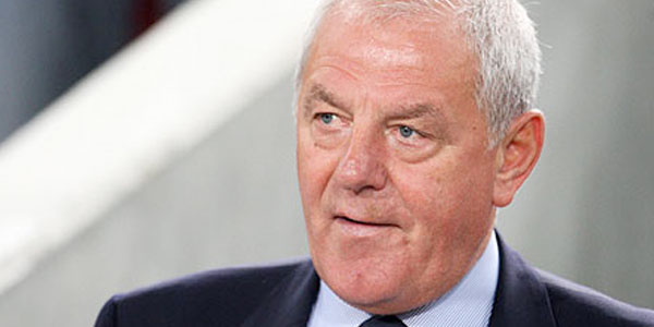 Observamos aca aun hombre mayor  con traje elegante que sonrie discretamente