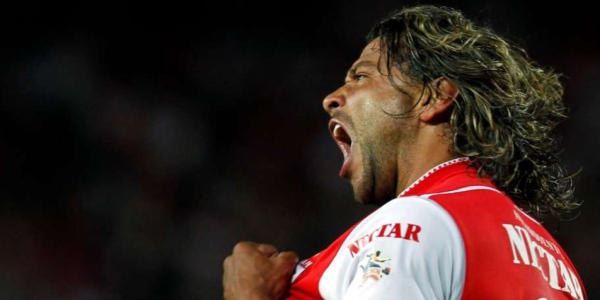 Un futbolista que grita en medio de la cancha lleva su uniforme rojo y blanco