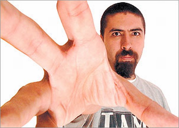 Un hombre con barba joven que muestra su mano  a la cámara