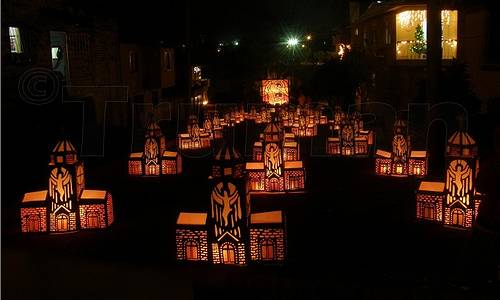 Vemos una  calle oscura en donde se ven muchos faroles encendidos hechos con hermosos motivos navideños