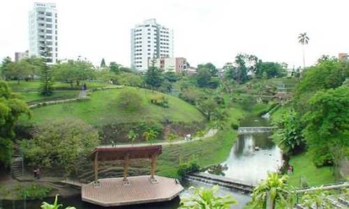 Vemos un parque con lago sendero ecologico muchas partes verdes bancas para sentarse a descasar esta en medio de una parte muy concurrida de la ciudad