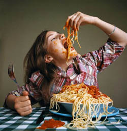 Vemos una niña que come de una forma desaforada espaguetis en un plato que contiene muchos
