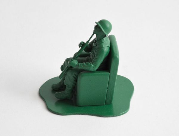 Vemos aun soldado sentado en un tanque con su fusil en las manos donde lo sostiene en la barbilla 