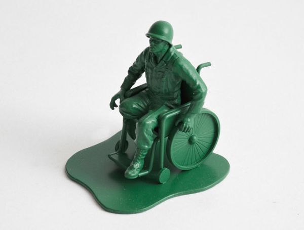 Tenemos a un joven soldado qu se inpulsa en una silla de ruedas es una figura de madrea