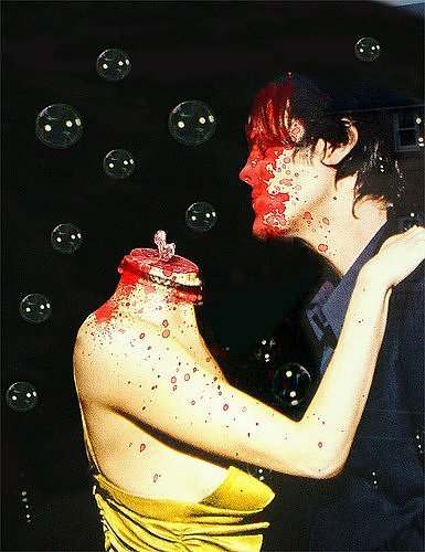 Un hombre con cara ensangrentada baila con una mujer que no tiene cabeza en medio de burbujas de jabon