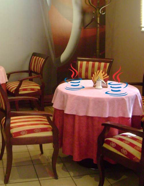 Vemos una mesa de comedor vestida con su mantel servilletas   y vemos  unos pocillos con cafe muy caliente que saca humo