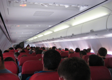 Vemos unas personas sentadas en un avion sus sillas son rojas