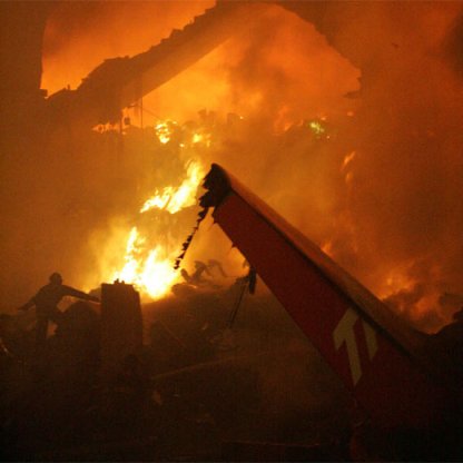 Vemos un avión entre llamas después de  una explosión vemos aun bombero que trata de avanzar  cerca de las llamas 