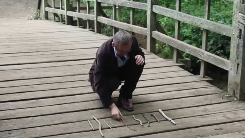 Un hombre mirando un palos puestos en el piso