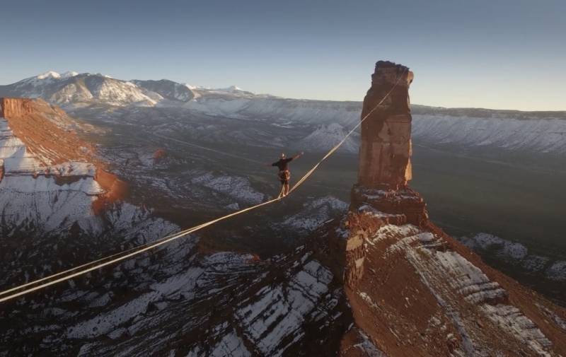 Un hombre caminando por una delgada cuerda que va de una montaña a otra