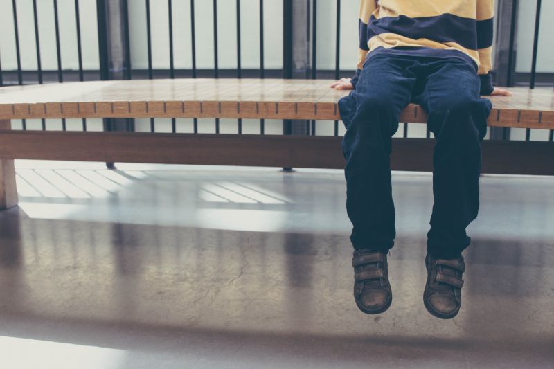 Foto a la mitad del cuerpo de un niño sentado en una banca