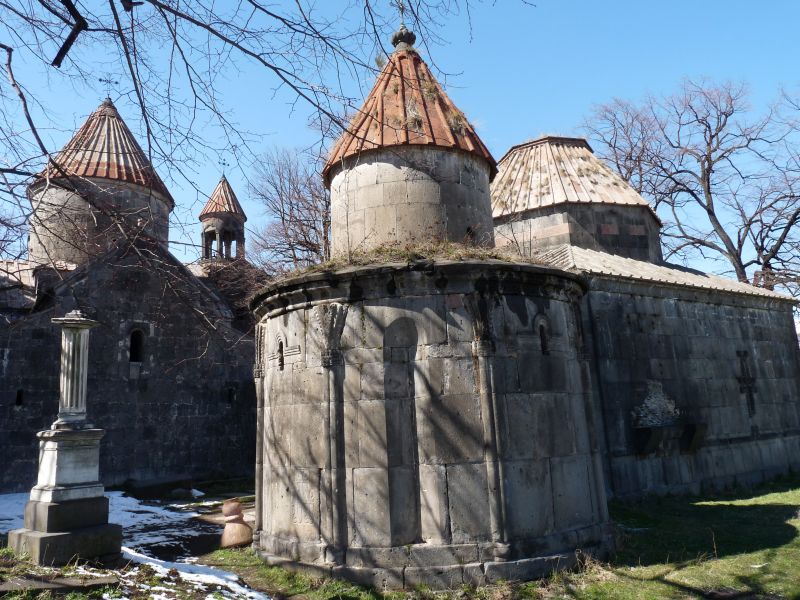 Foto del monasterio fortalecido de paredes altas de cemento en un prado con arboles secos