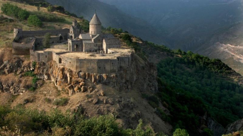Foto de una iglesia hecha en un acantilado rodeado de montañas