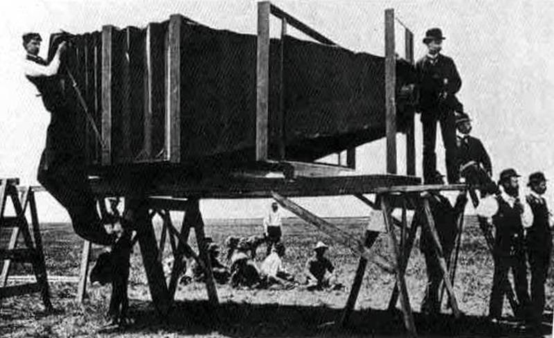 Varios hombres rodeando a un par de hombres que están al lado de una caja grande y oscura